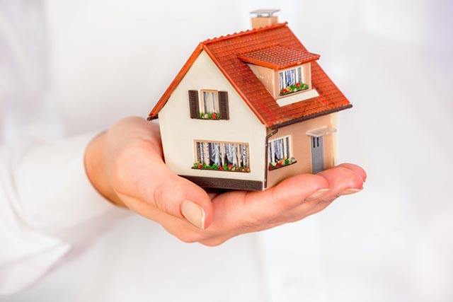 a-miniature-house-with-a-red-roof-being-held-in-a-persons-hand
