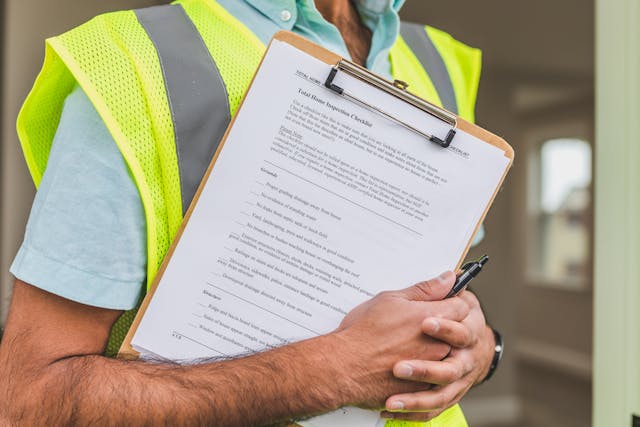 person in neon vest holding a home inspection checklist